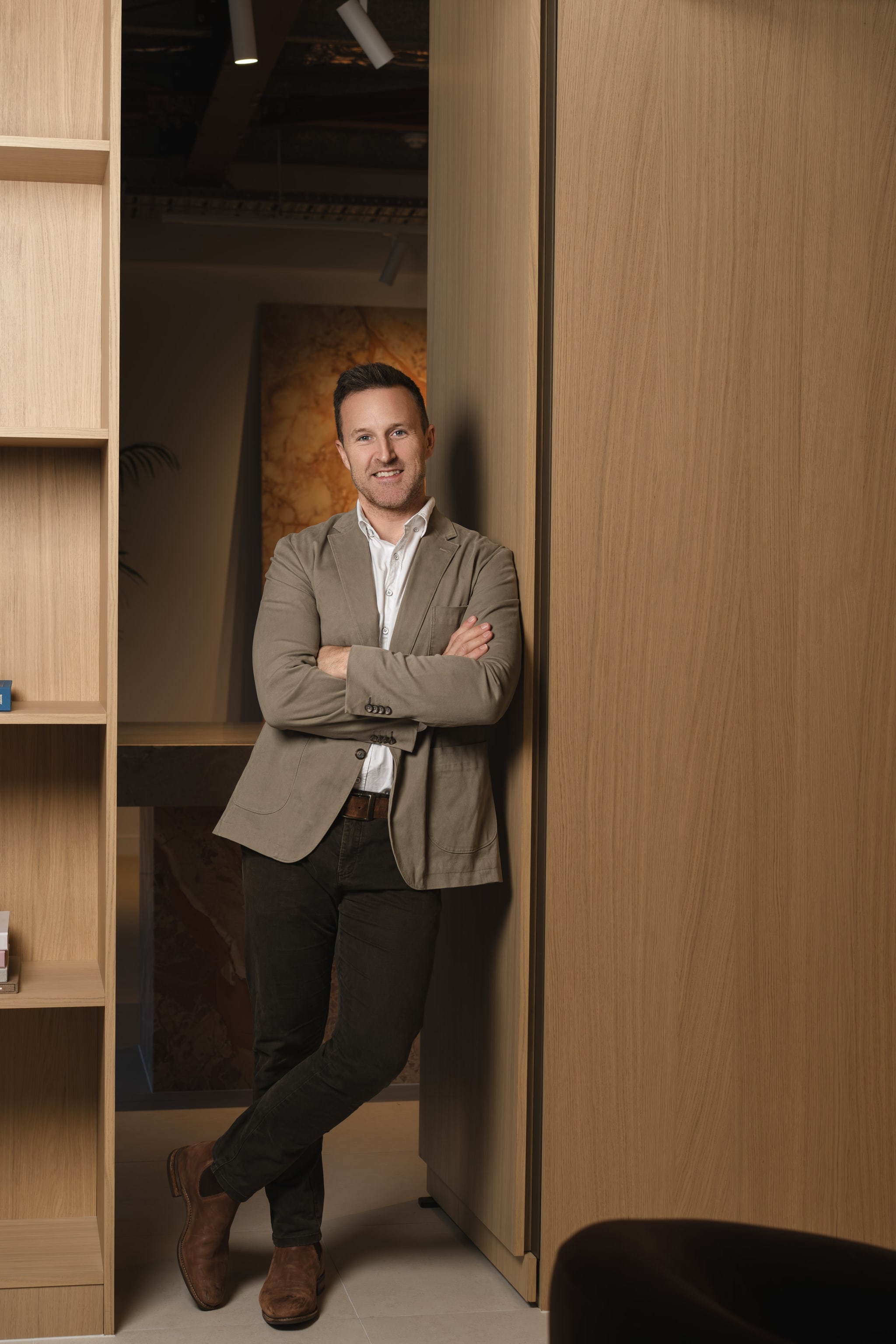 Founder in tan blazer leaning against a wood column. Spyre Group