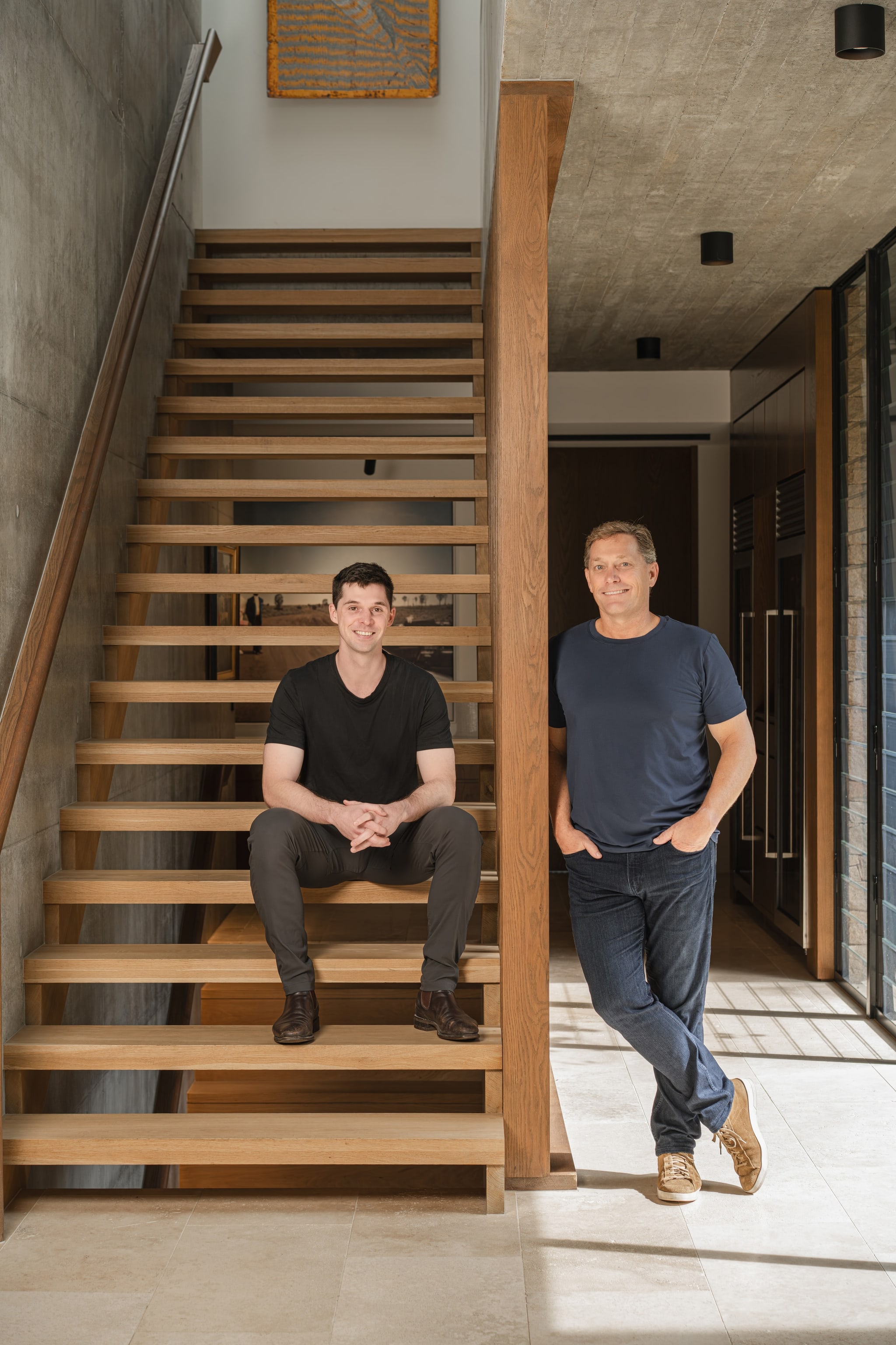 Two founders on a timber-and-concrete staircase. TH7