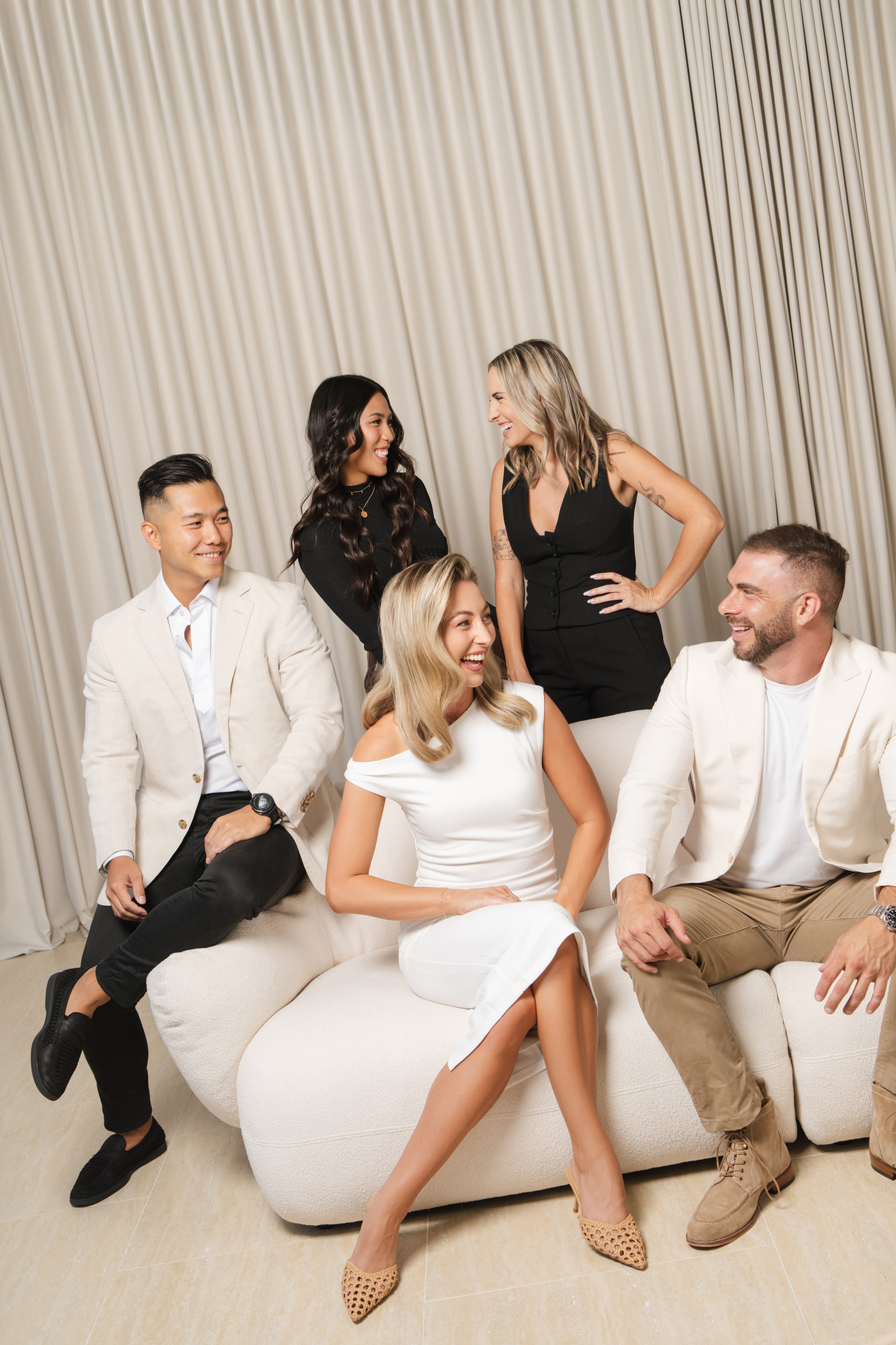 Space Property group portrait. Five executives on a cream sofa against a pleated curtain backdrop.